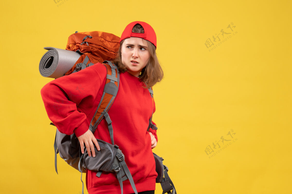 成人正面图：年轻的女旅行者 手放在腰间 背着背包姿势帽子前面
