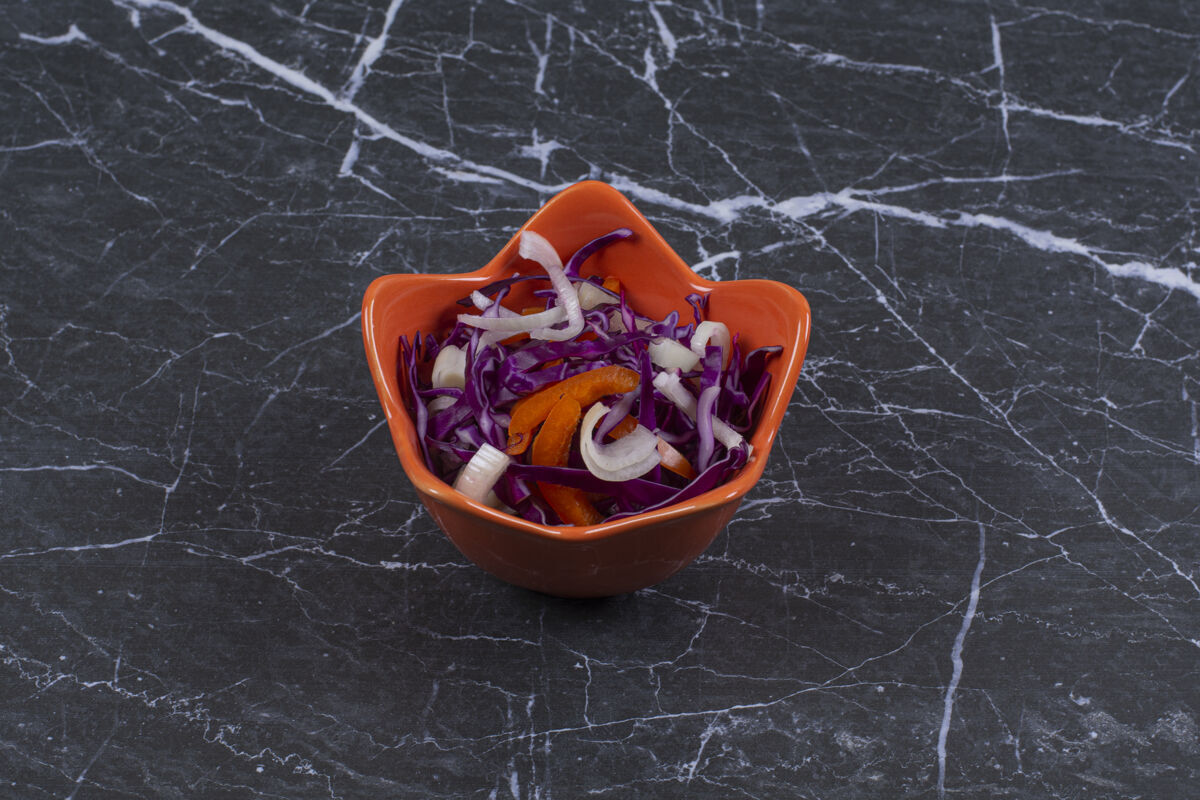 木材新鲜蔬菜沙拉 放在黑石头上的橙色碗里菜肴健康胡椒