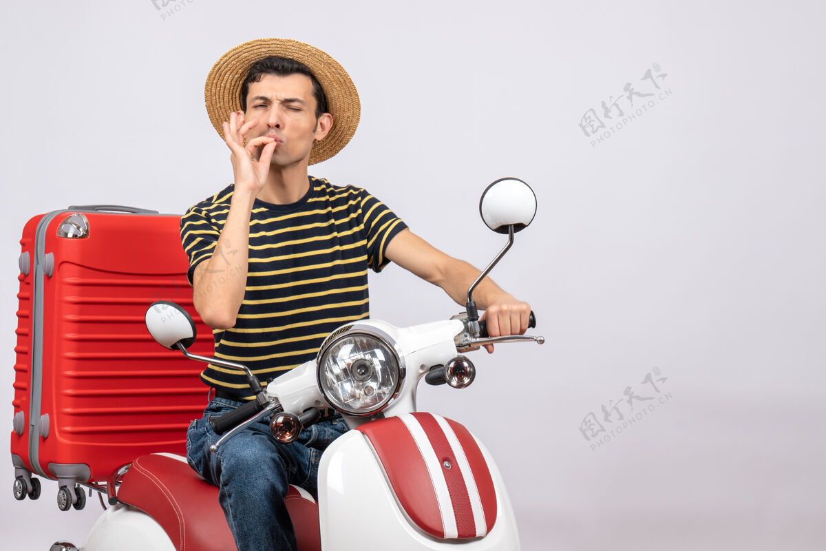 前面骑着轻便摩托车戴着草帽的年轻人的正面图 做着美味的招牌轻便摩托车稻草车辆