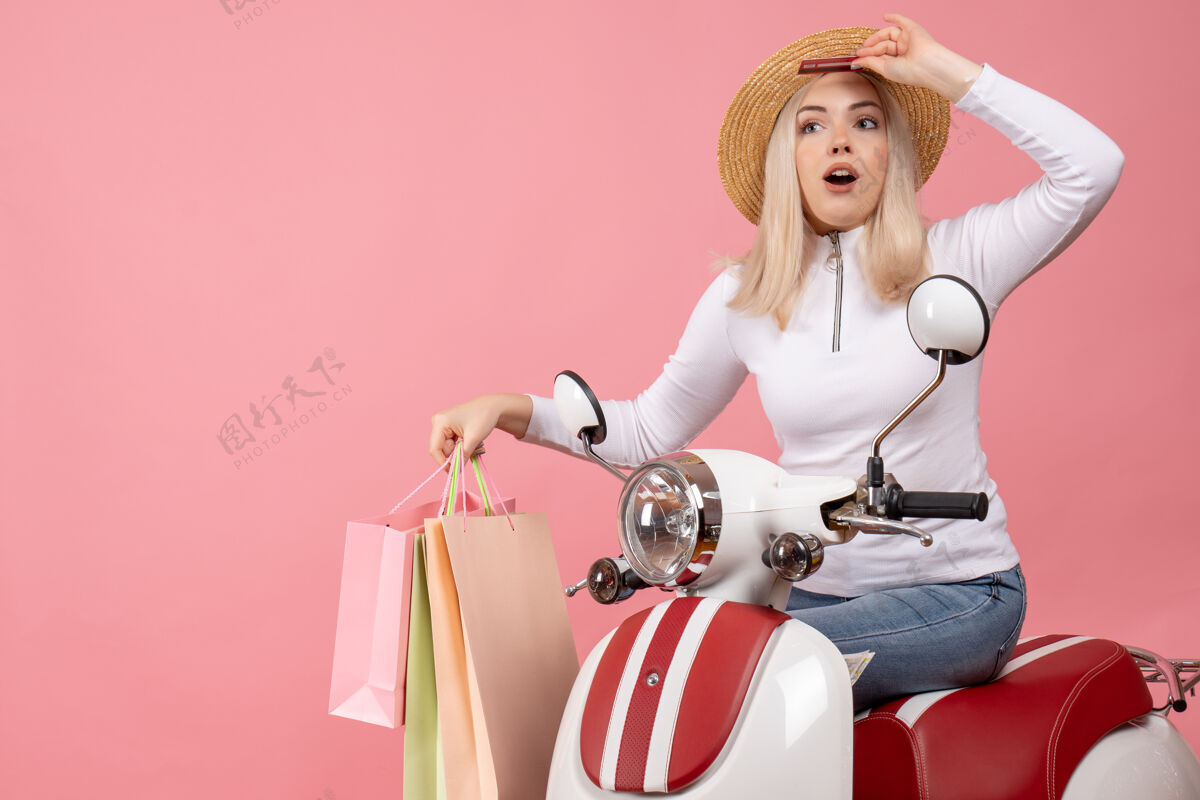 前面正面图：骑着轻便摩托车的年轻女士手里拿着购物袋 急急忙忙摩托车时尚年轻女士