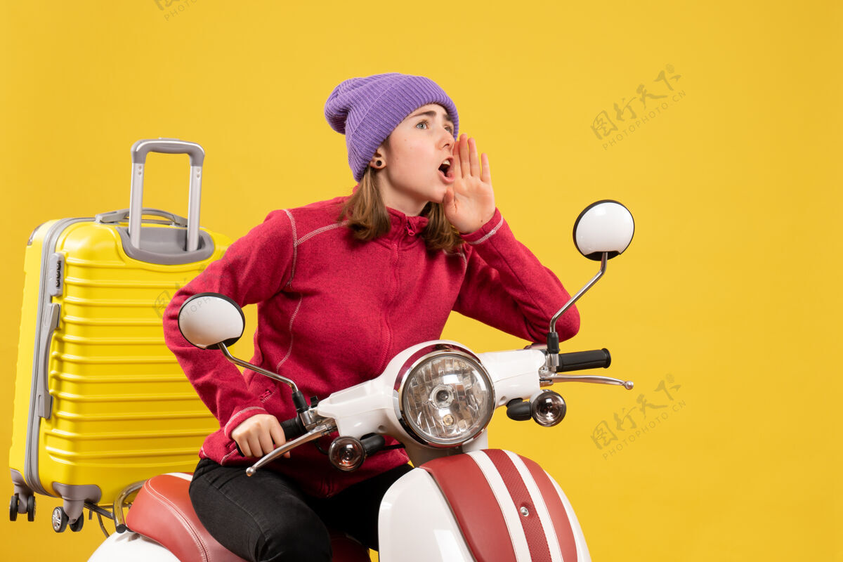 年轻女孩前视图骑着轻便摩托车的年轻女孩在叫人轻便摩托车呼叫成人