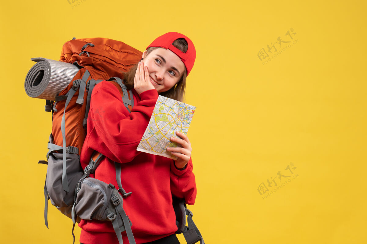 帽子前视图微笑的女露营者与红色背包举行旅游地图背包抱着前面