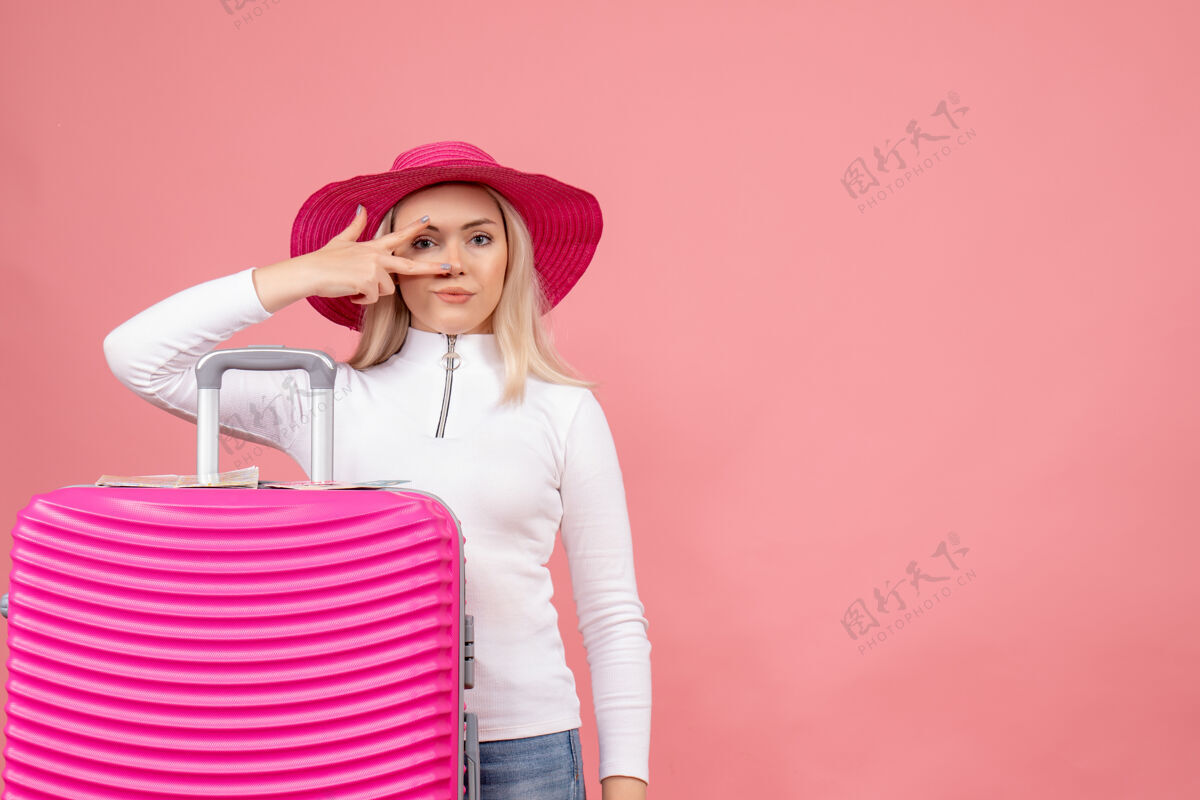 欢乐正面图：站在粉色手提箱后面的年轻漂亮女士女士成人礼物