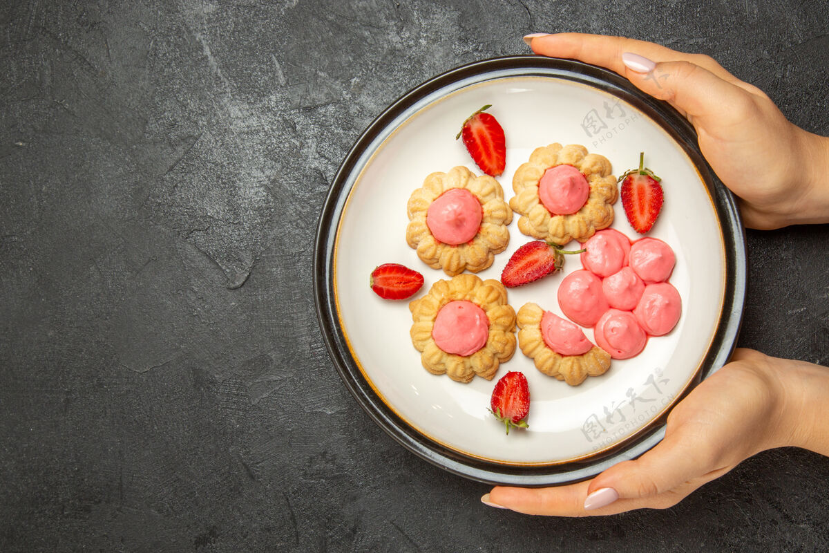 早餐顶视图美味的小饼干与粉红色奶油内板在灰色的表面营养品桌子饼干