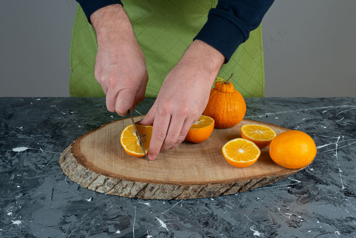 橙子男人的手在大理石桌上拿着橘子汁围裙男有机