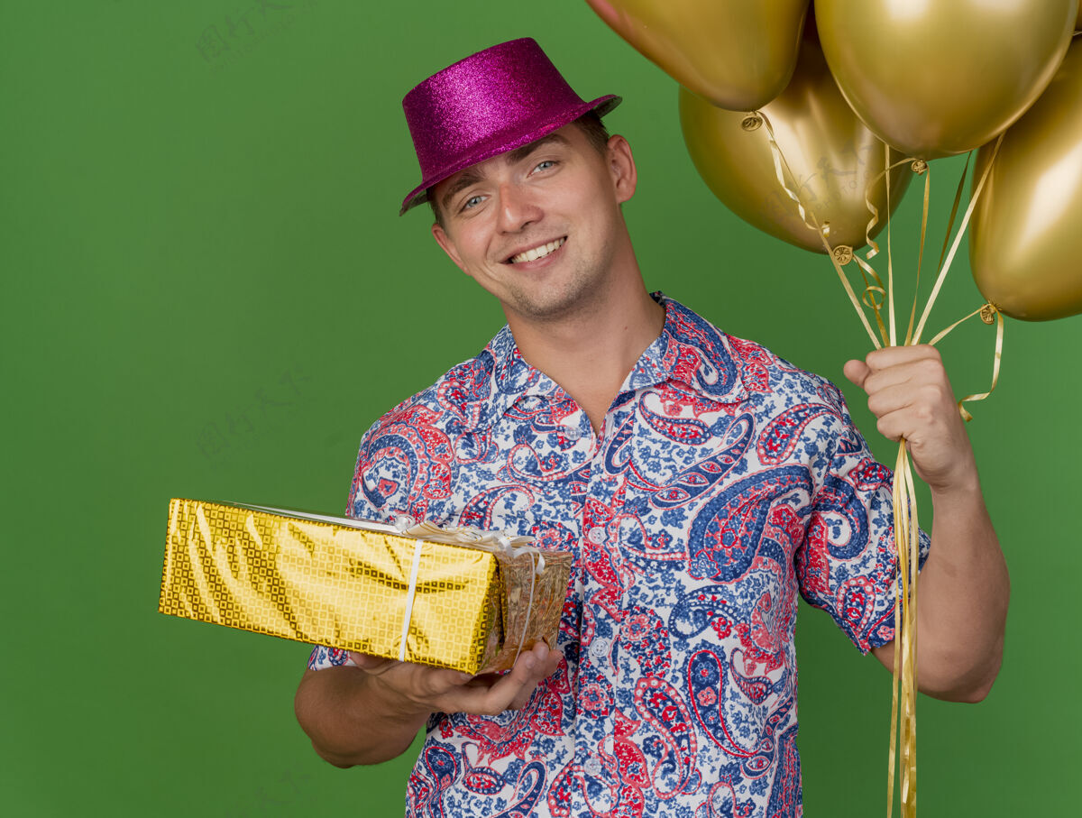 粉色微笑着的年轻人戴着粉红色的帽子拿着气球和礼品盒隔离在绿色礼物年轻人帽子