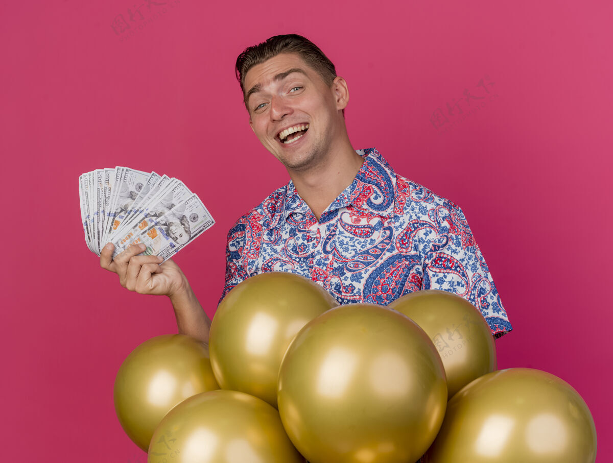 粉色面带微笑的年轻人穿着五颜六色的衬衫站在气球后面 手里拿着粉红色的钞票现金抱着年轻人