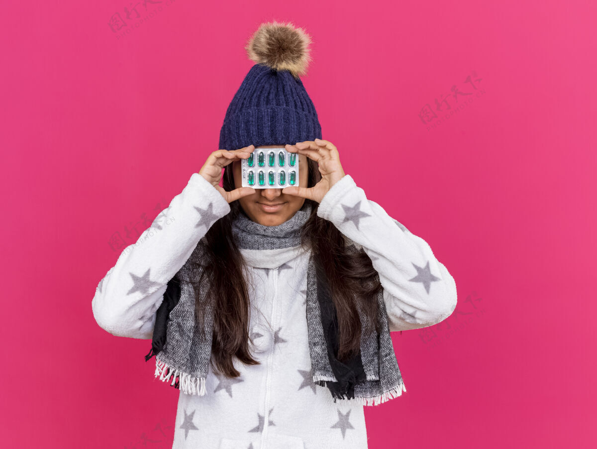 年轻年轻生病的女孩戴着冬天的帽子 戴着围巾 眼睛上涂着粉红色的隔离药丸眼睛围巾粉红色