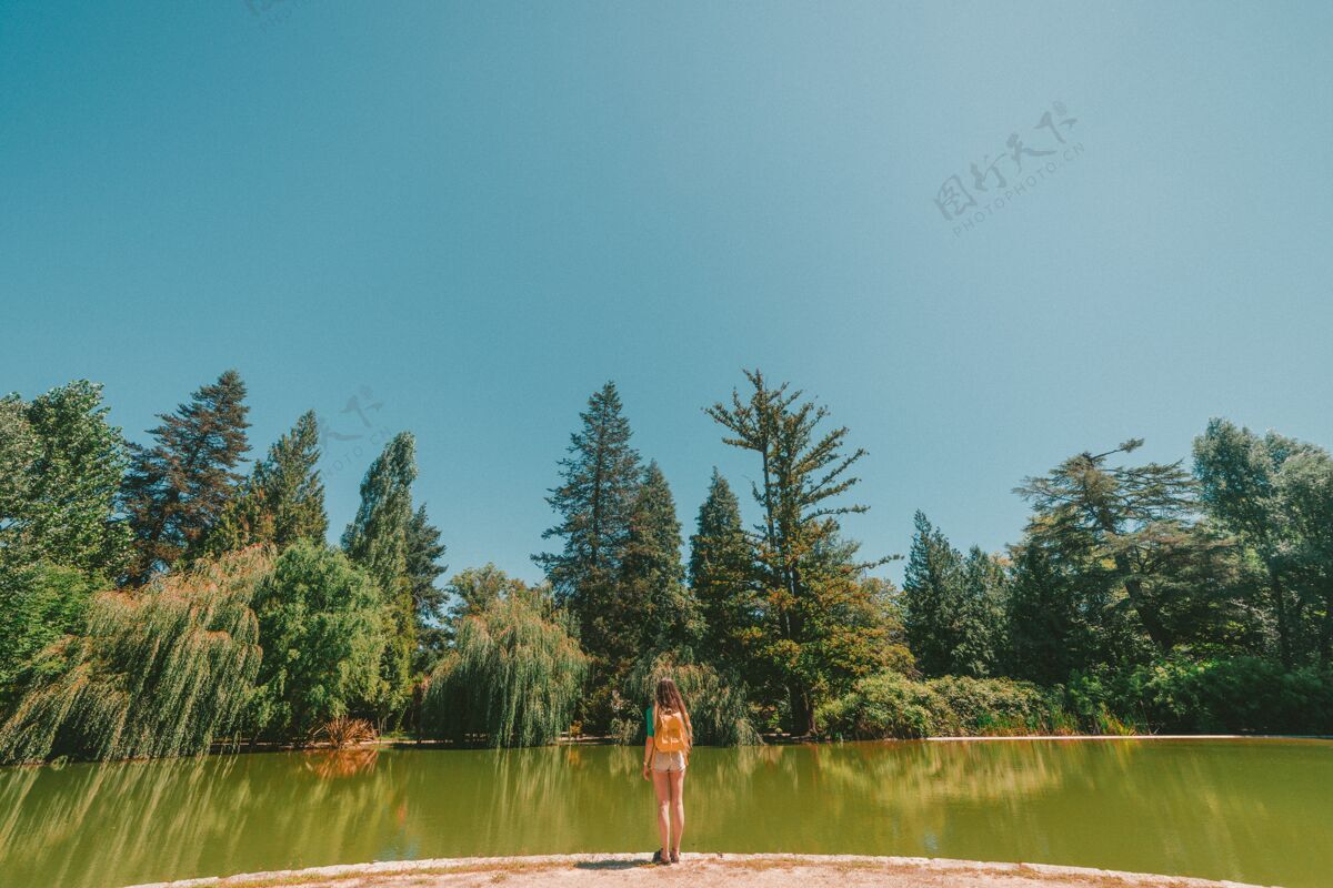 人在一个炎热的天气里 一个女人站在森林中间的一条河的前面度假休闲绿色