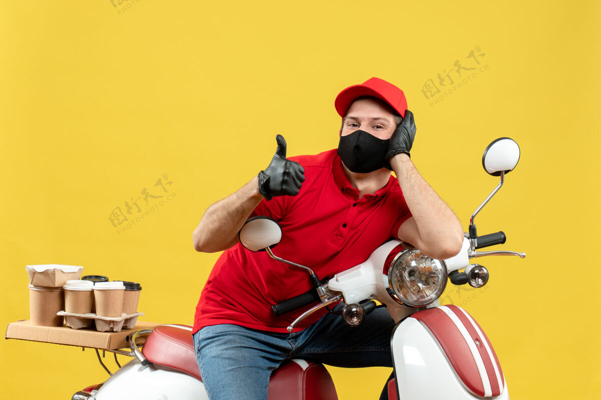 前面正面图微笑的快递员身穿红色上衣 戴着帽子手套 戴着医用口罩 坐在滑板车上做着“ok”的手势手套制造面罩