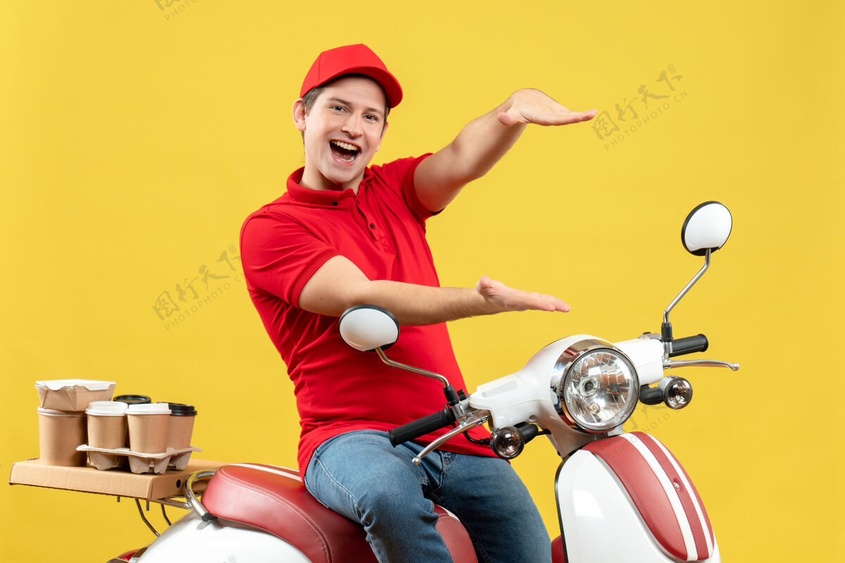 背景正面是一个穿着红色上衣戴着帽子的快乐的年轻人 在黄色的背景下发订单年轻人帽子人