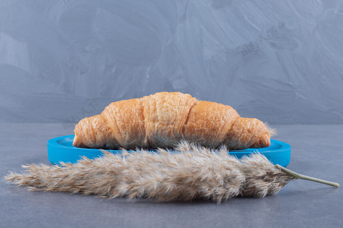 桌子新鲜出炉的法式羊角面包放在蓝色木板上美食美味许多