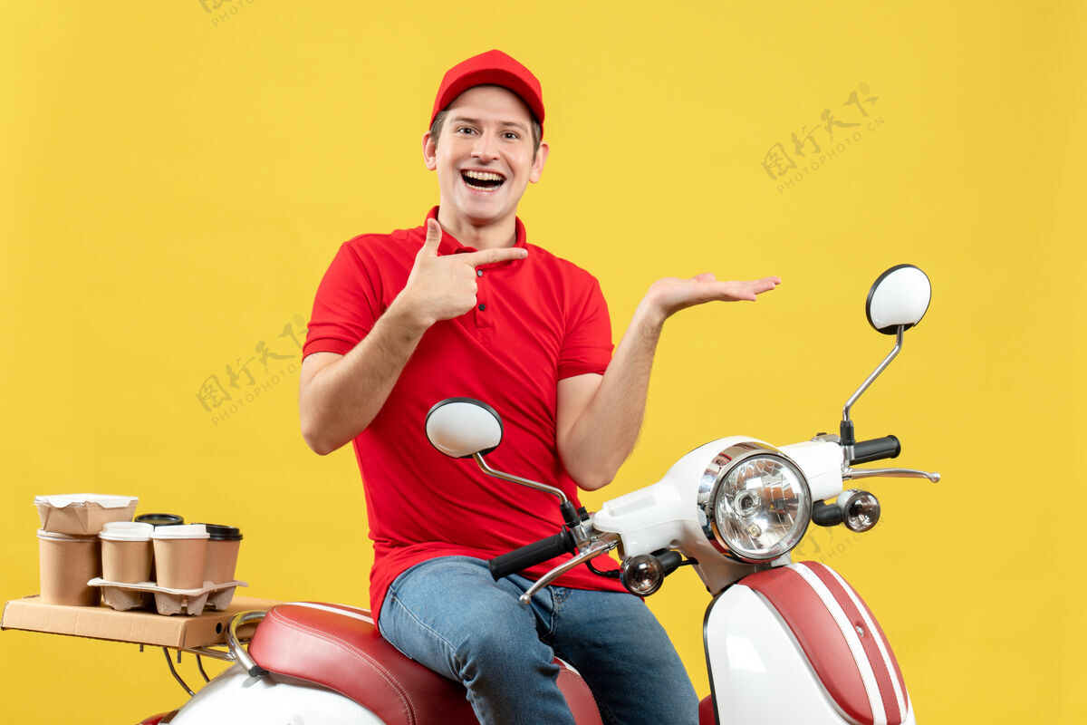 车辆正面图是一个穿着红色上衣 戴着帽子 面带微笑 心情愉快的年轻人 在黄色背景上 他指着左边的某个东西发命令东西人红色