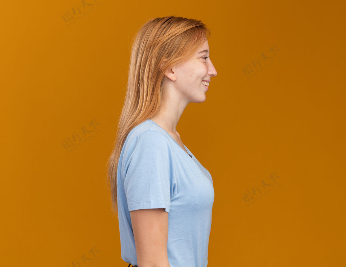 姜黄色笑容可掬的年轻红发姜汁女孩站在橙色的一边 脸上有雀斑雀斑侧着橙色