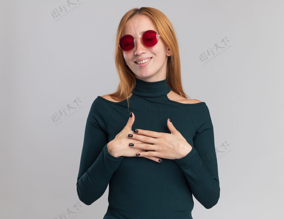 眼镜戴着太阳镜满脸雀斑的年轻红发姜女高兴地把手放在白色的胸前胸部请红发