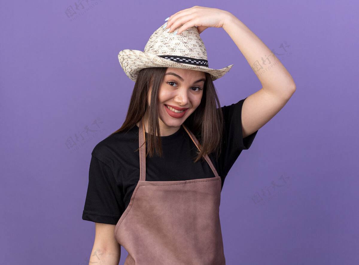 漂亮微笑着美丽的白人女园丁戴着一顶紫色的园艺帽园艺手帽子