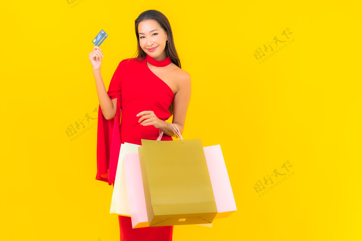 信用卡带购物袋和信用卡的美丽亚洲年轻女子肖像持有多彩购买