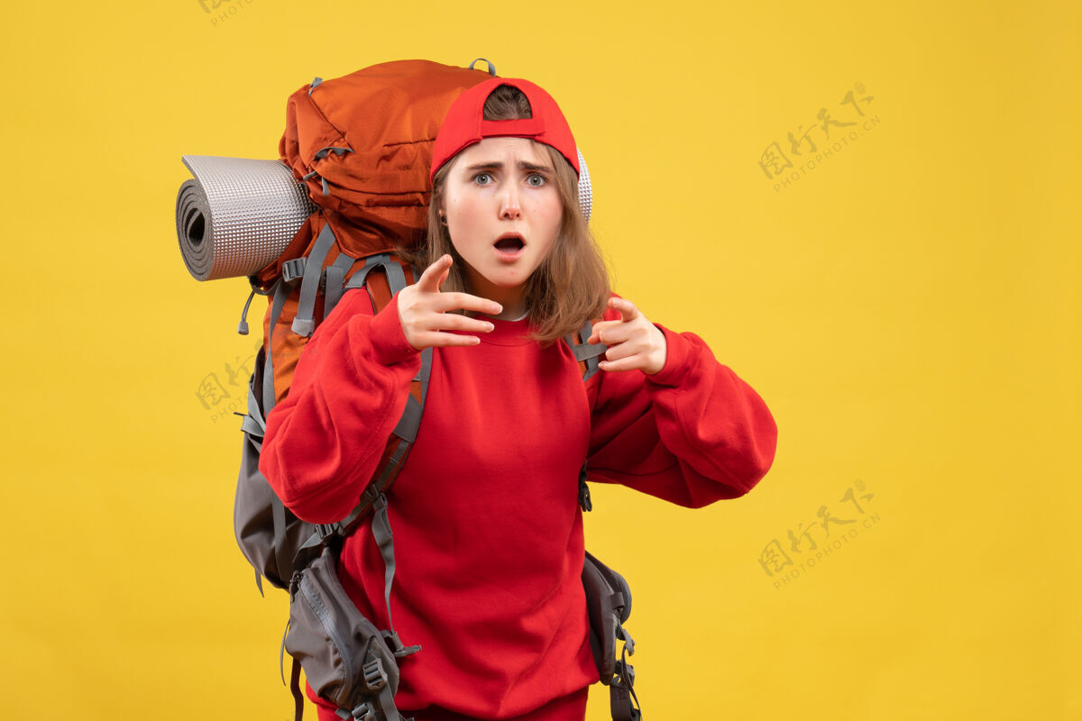 人正面图酷酷的女旅行者背着背包用手指指着相机背包漂亮前面