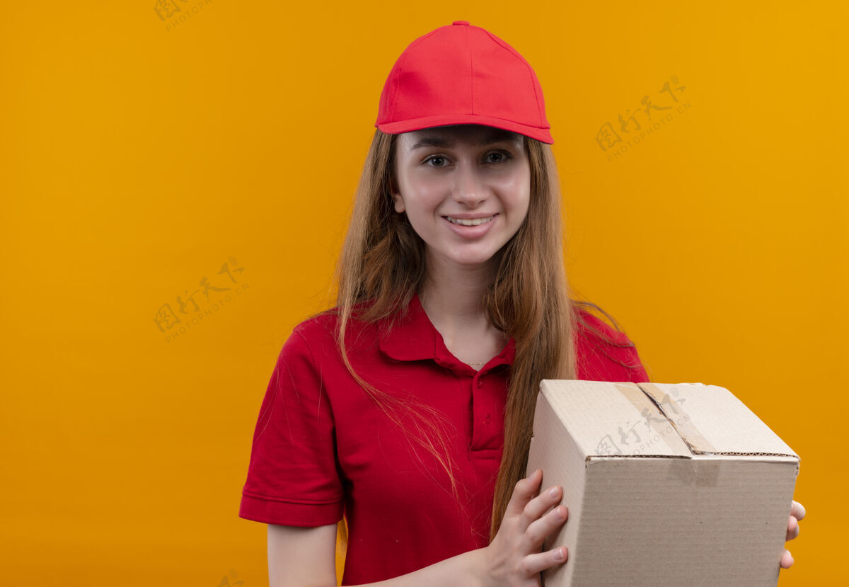 盒子微笑的年轻送货女孩在红色制服举行孤立的橙色空间与复制空间框年轻复制拿着