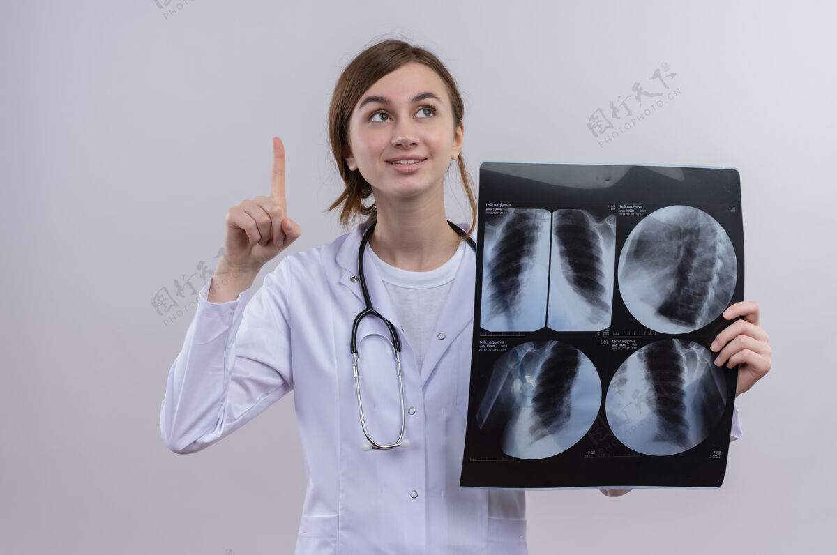 手指年轻的女医生穿着医用长袍 戴着听诊器 举着x光片举起手指医生年轻长袍
