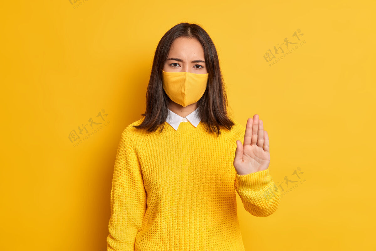 穿着停止病毒严重愤怒的亚洲女人保持手掌向前拉的停止手势 戴上防护面具以防冠状病毒人姿势冬季
