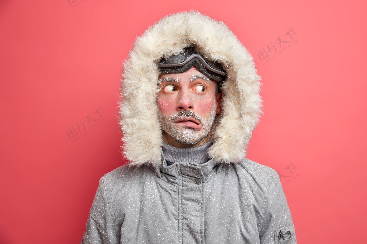 夹克情绪困惑的男人把头捂着嘴唇 一边看着因低温发抖需要保暖的灰色夹克和皮帽霜保温瓶风