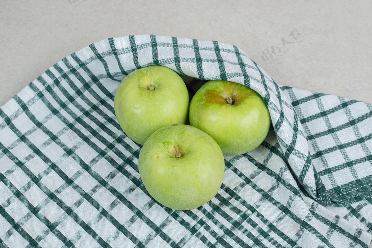有机整个青苹果在条纹桌布上熟的营养新鲜