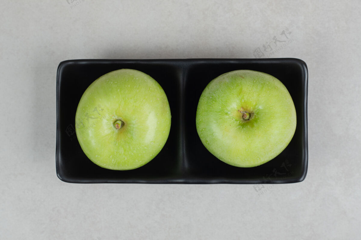 新鲜新鲜的青苹果放在黑盘子里食品熟的美味