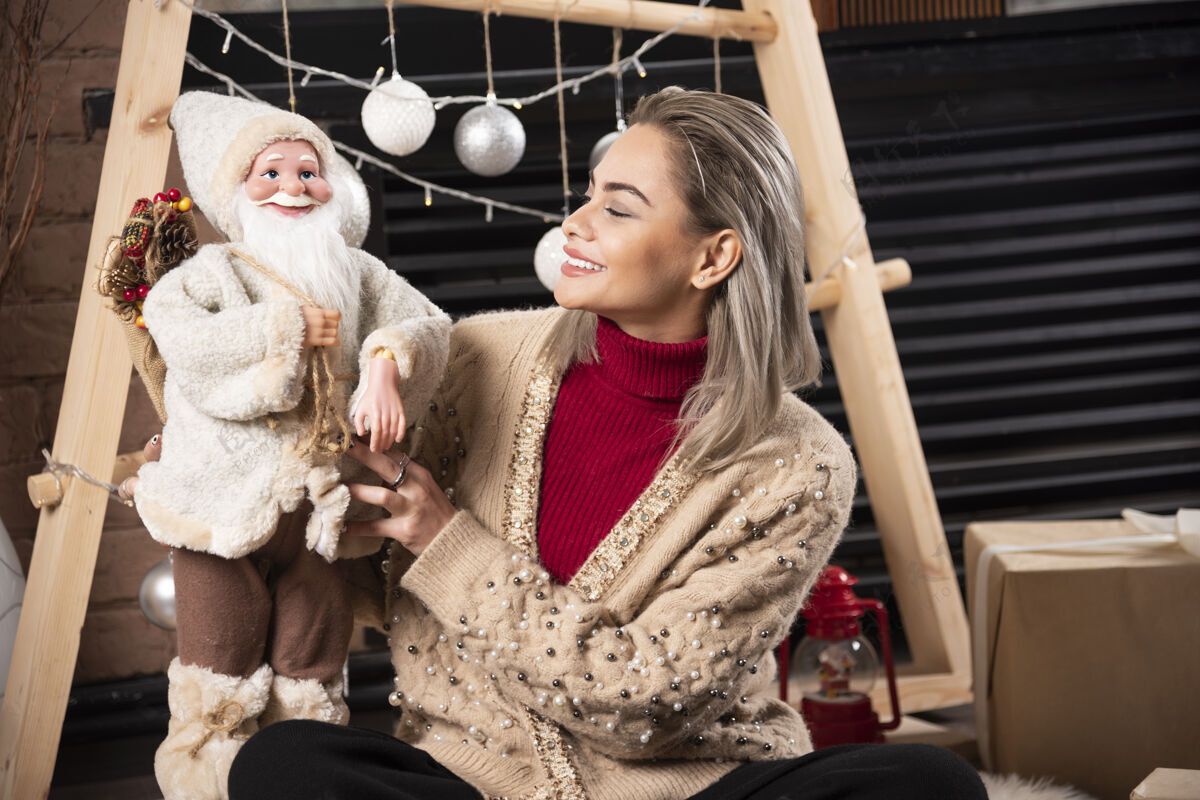 成人年轻女子坐着和圣诞老人玩具摆姿势的肖像高质量的照片可爱年轻微笑