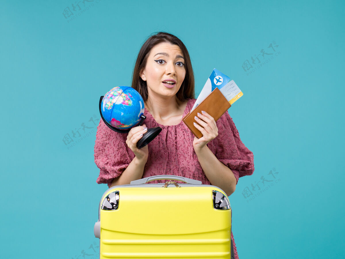 球前景度假女拿着地球仪和飞机票在蓝色书桌上海上度假女旅行暑假微笑女人举行