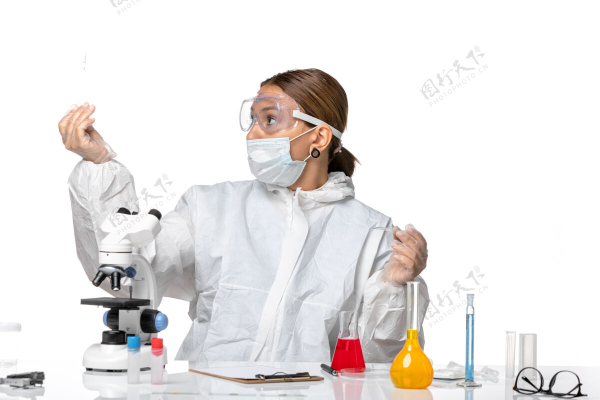 女医生前视图穿着防护服 戴着口罩的女医生正在用浅白色背景的冠状病毒大流行病毒的溶液工作医疗视图医生