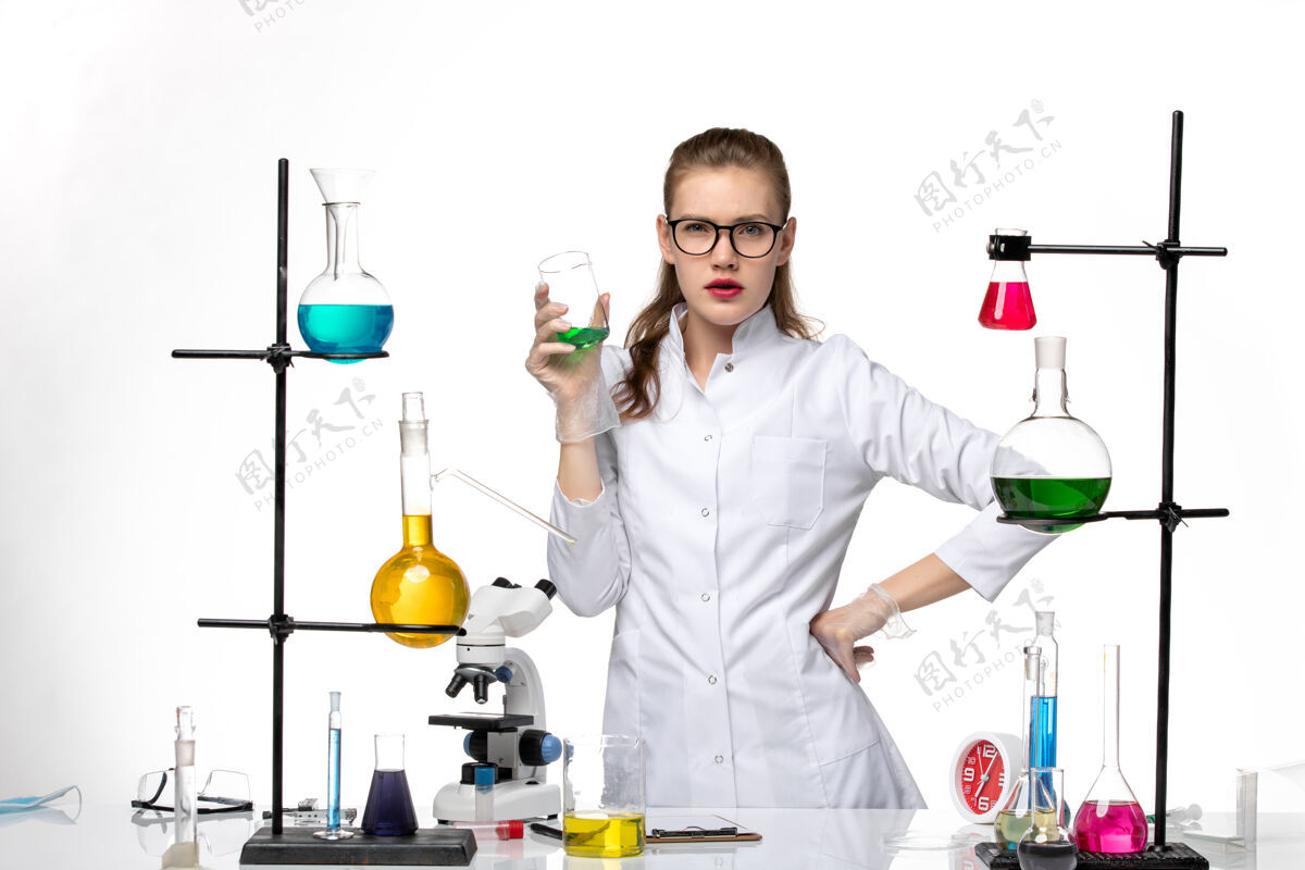 人前视图身着医疗服的女化学家在工作过程中用浅白背景上的溶液化学大流行的病毒医学专业浅白