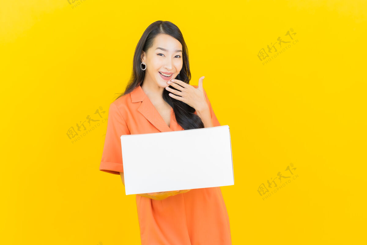泰国肖像美丽的年轻亚洲妇女与箱准备装运黄色控股笔记本电脑盒子