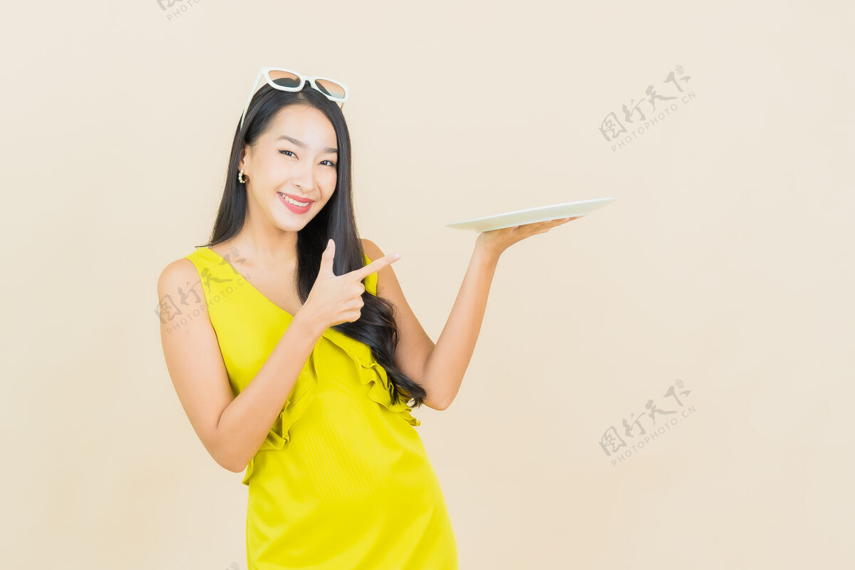 喜悦画像美丽的亚洲年轻女子微笑着在彩色墙上的空盘子女士盘子亚洲