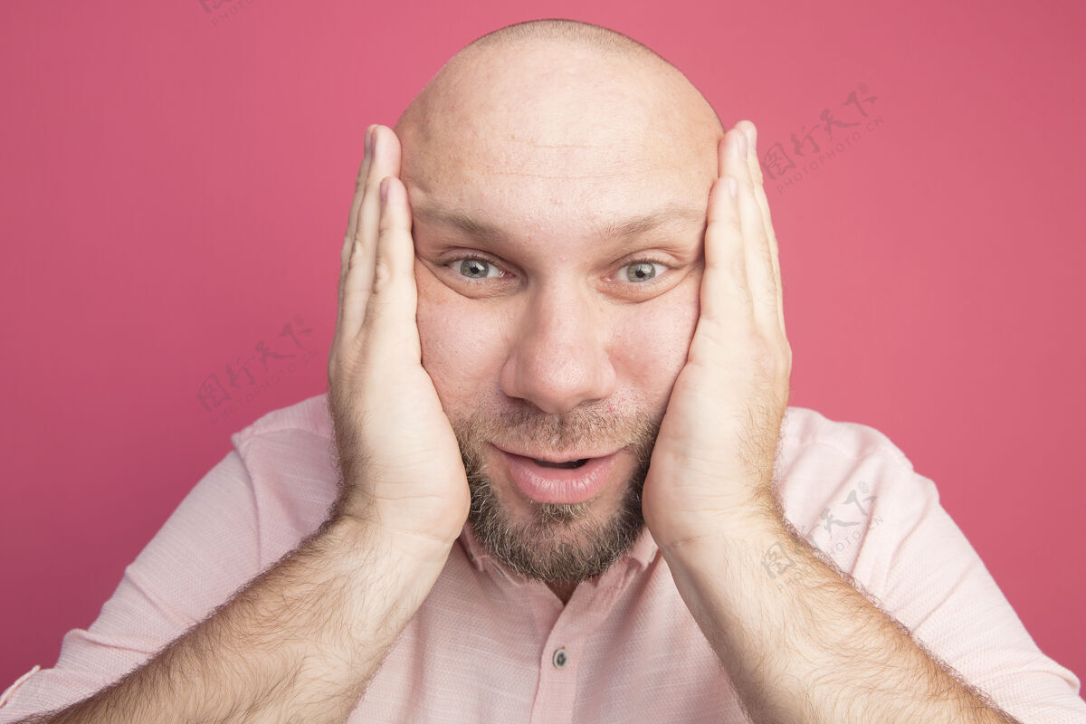手惊讶的中年秃头男子穿着粉色t恤 双手放在脸颊上男人脸颊惊喜