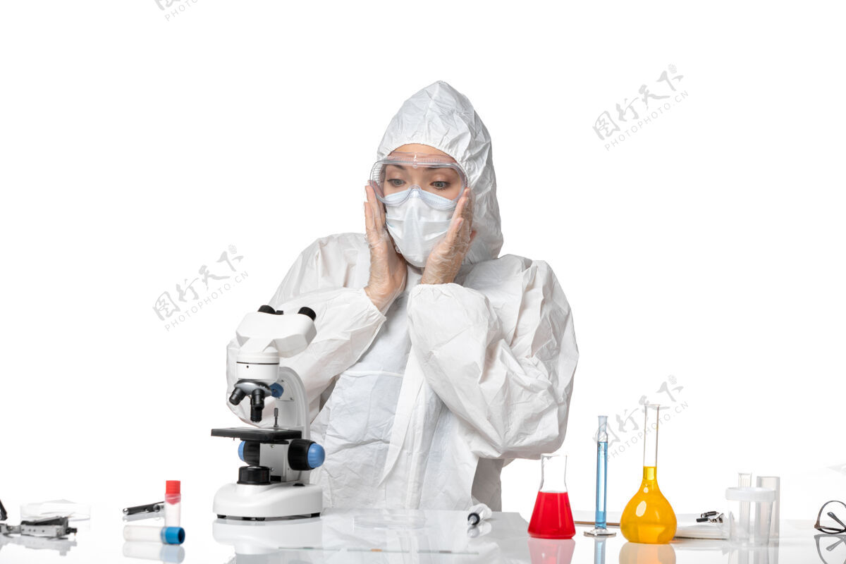口罩正面图女医生穿着防护服 戴着口罩 由于使用显微镜观察到白色背景病毒大流行飞溅的covid-医生专业制服