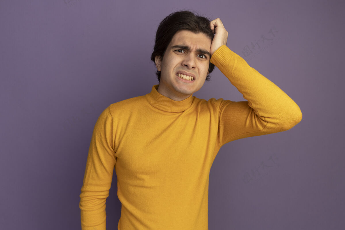 人关心的年轻帅哥穿着黄色高领毛衣把手放在太阳穴隔离在紫色的墙上高领毛衣穿着手