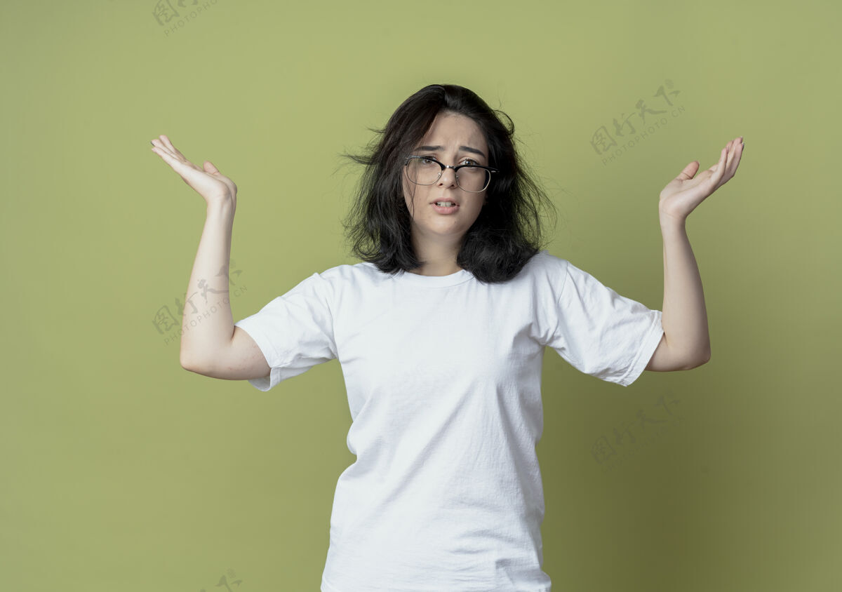 女孩迷茫的年轻漂亮的高加索女孩在橄榄绿的背景下露出空空的双手背景困惑显示