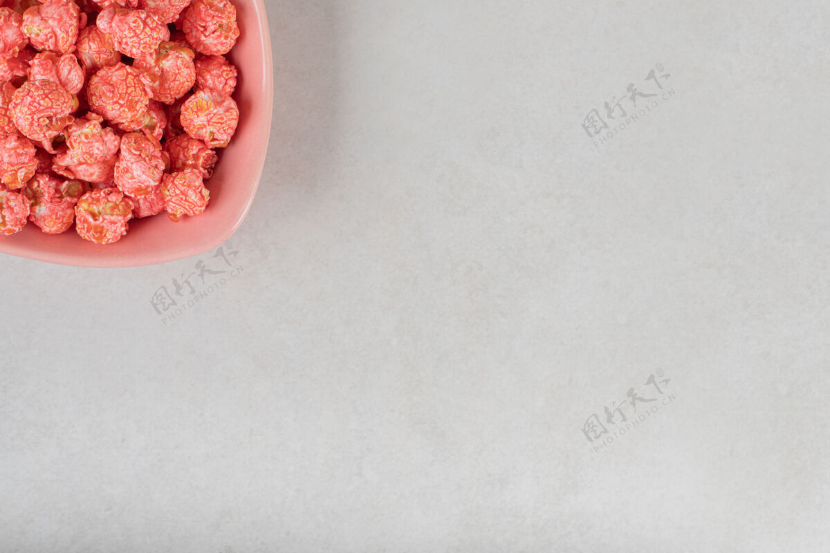 复制空间粉红色的碗里放着一份爆米花糖放在大理石桌上爆米花外套小吃
