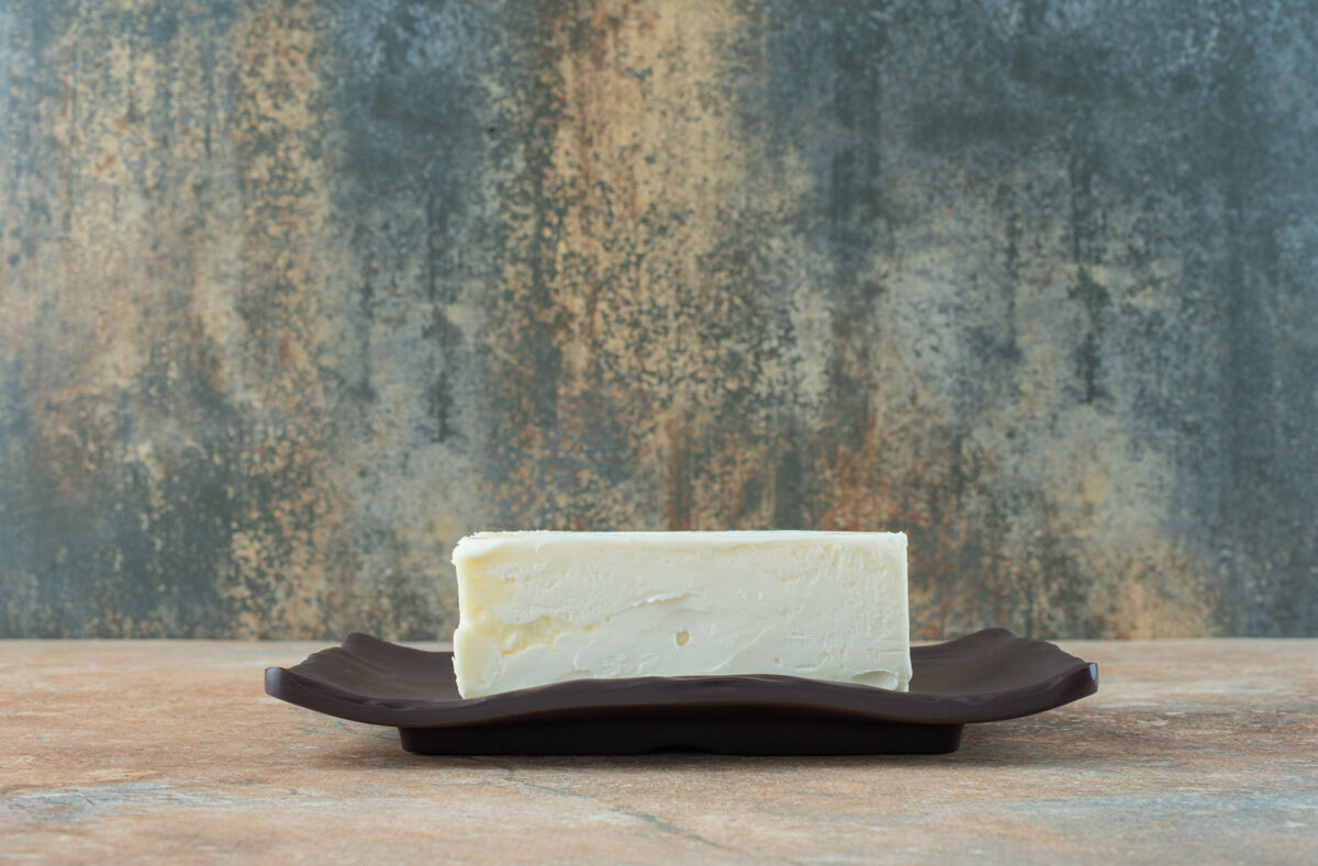 可口大理石桌上深色盘子上的白奶酪美味盘子美味