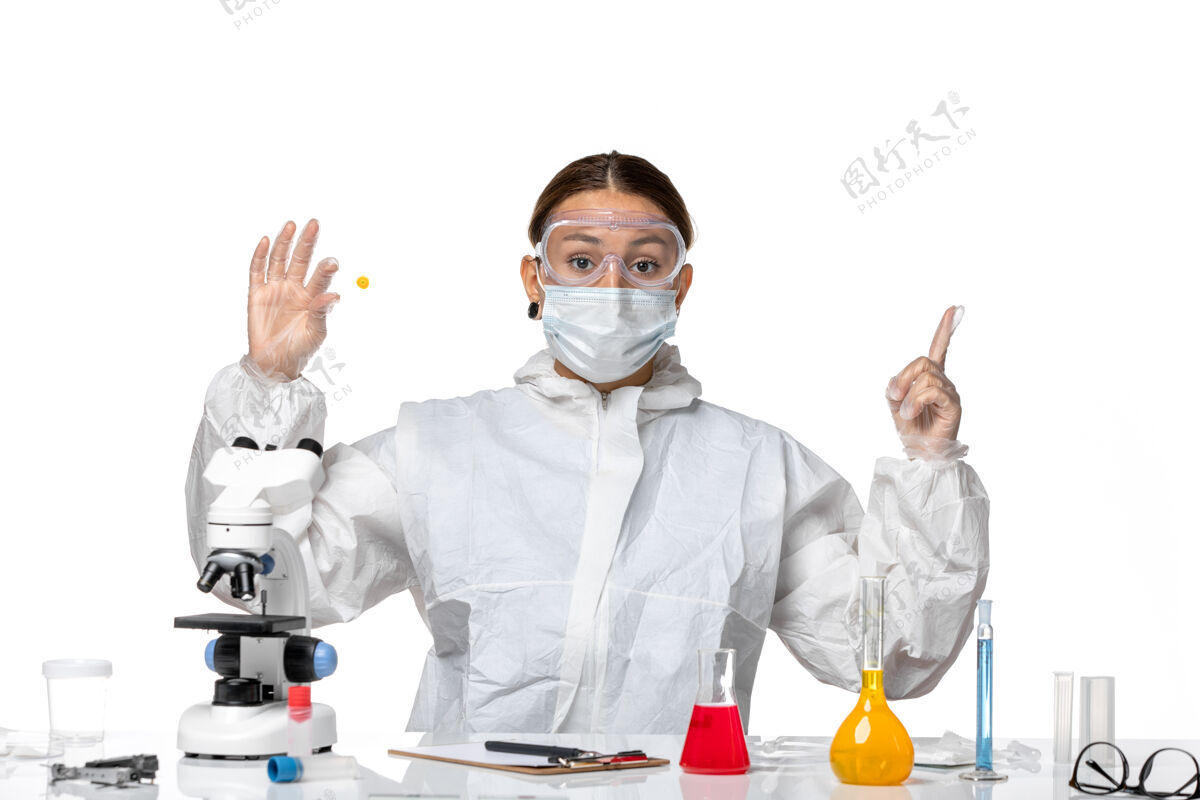 专业正面图：穿着防护服 戴着口罩的女医生 在白色桌子上拿着样本——大流行病毒人女医生白人