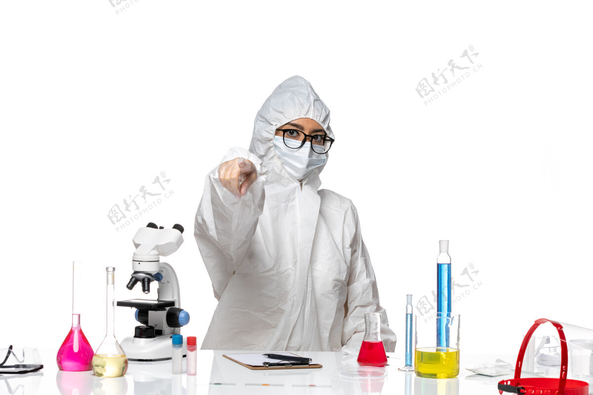 外套前视图穿着特殊防护服的女化学家指着白色背景的病毒实验室面具化学药