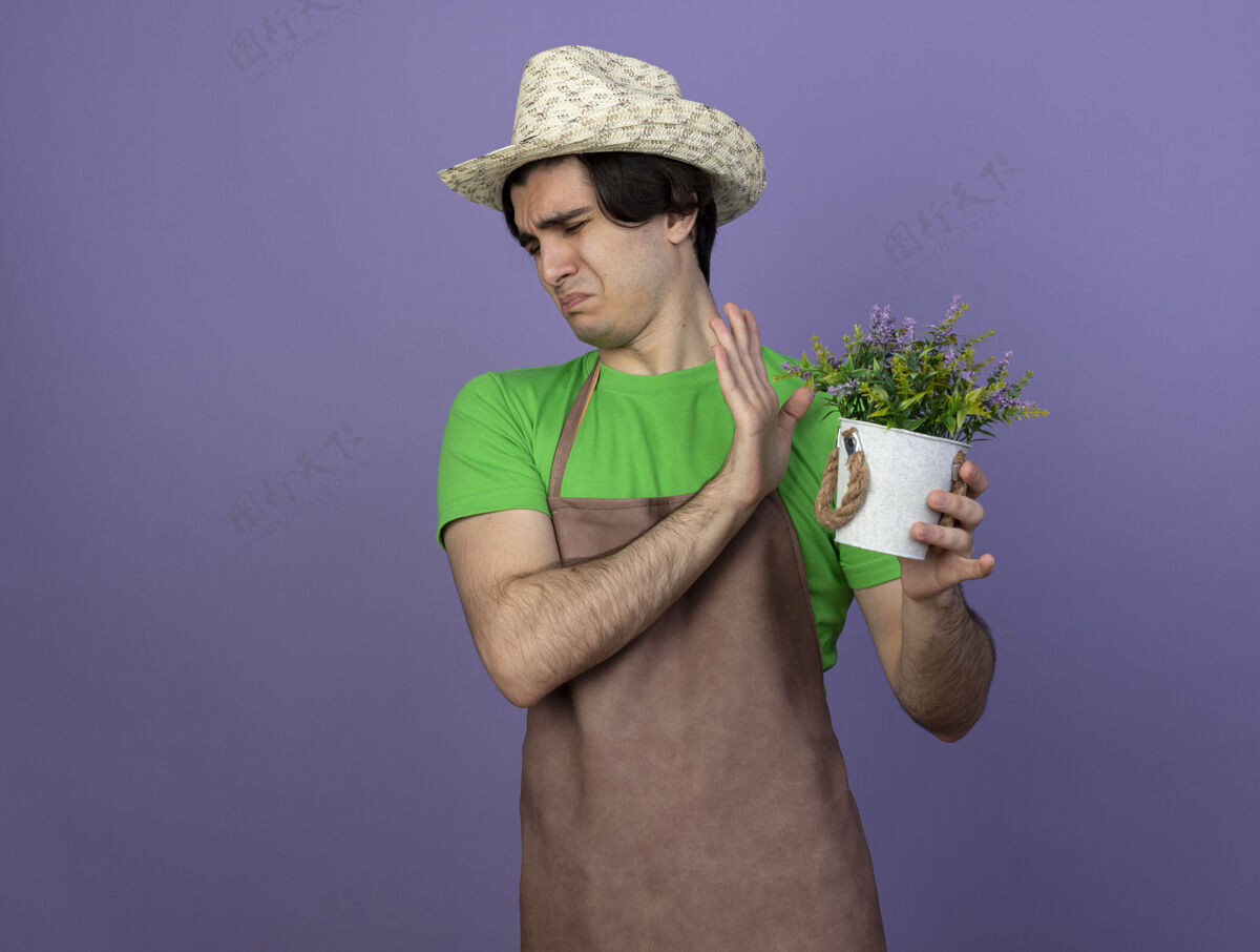男人穿着制服 戴着园艺帽 手里拿着花盆里的花 神经质的年轻男园丁制服花园男人
