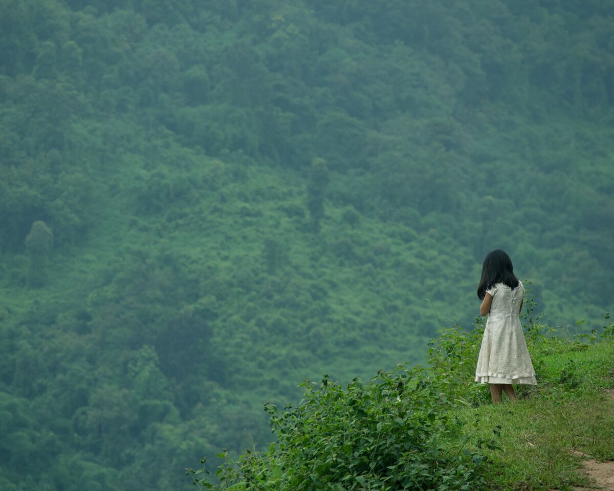 户外选择性聚焦拍摄一个年轻的女性站在悬崖上看绿色的自然独处娱乐悬崖