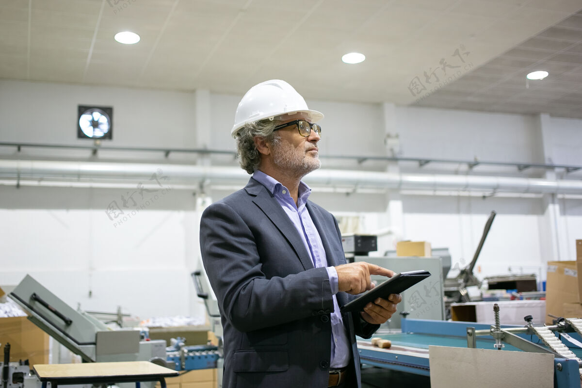 老板认真的主管在白盔上拿着平板电脑 看着生产过程西装工厂内容