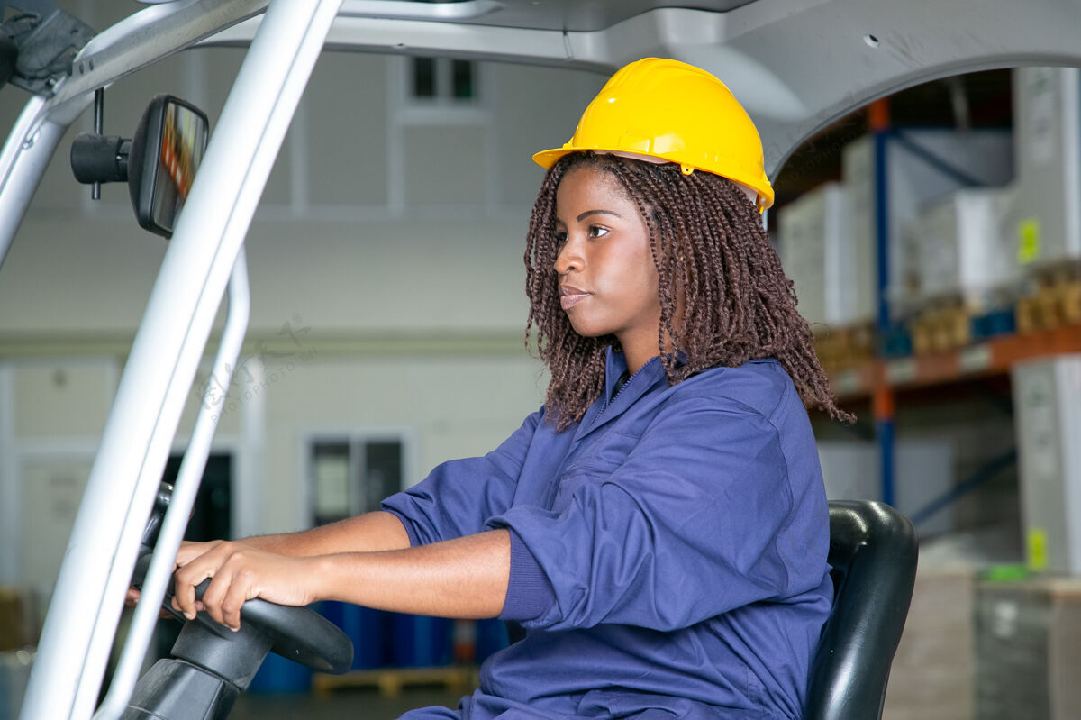 工厂穿着防护服的严肃年轻女物流工人在仓库里驾驶叉车车轮货物装运
