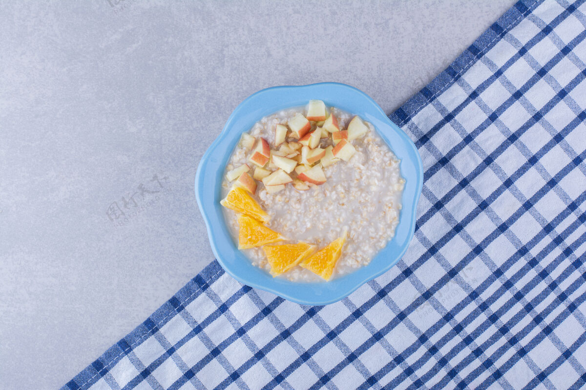 谷物一小碗燕麦片放在毛巾上 上面放着切好的苹果和橙子碎片 放在大理石表面毛巾苹果营养