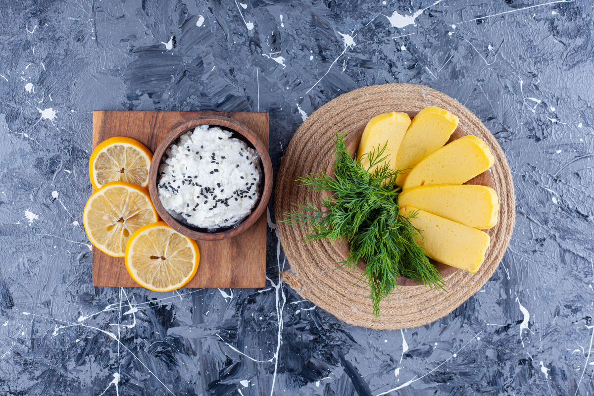 风味奶酪和莳萝放在一个碗里 放在一个三角架上 旁边是一碗奶酪和一块柠檬片 放在一块木板上 蓝色的表面上柠檬碗奶酪