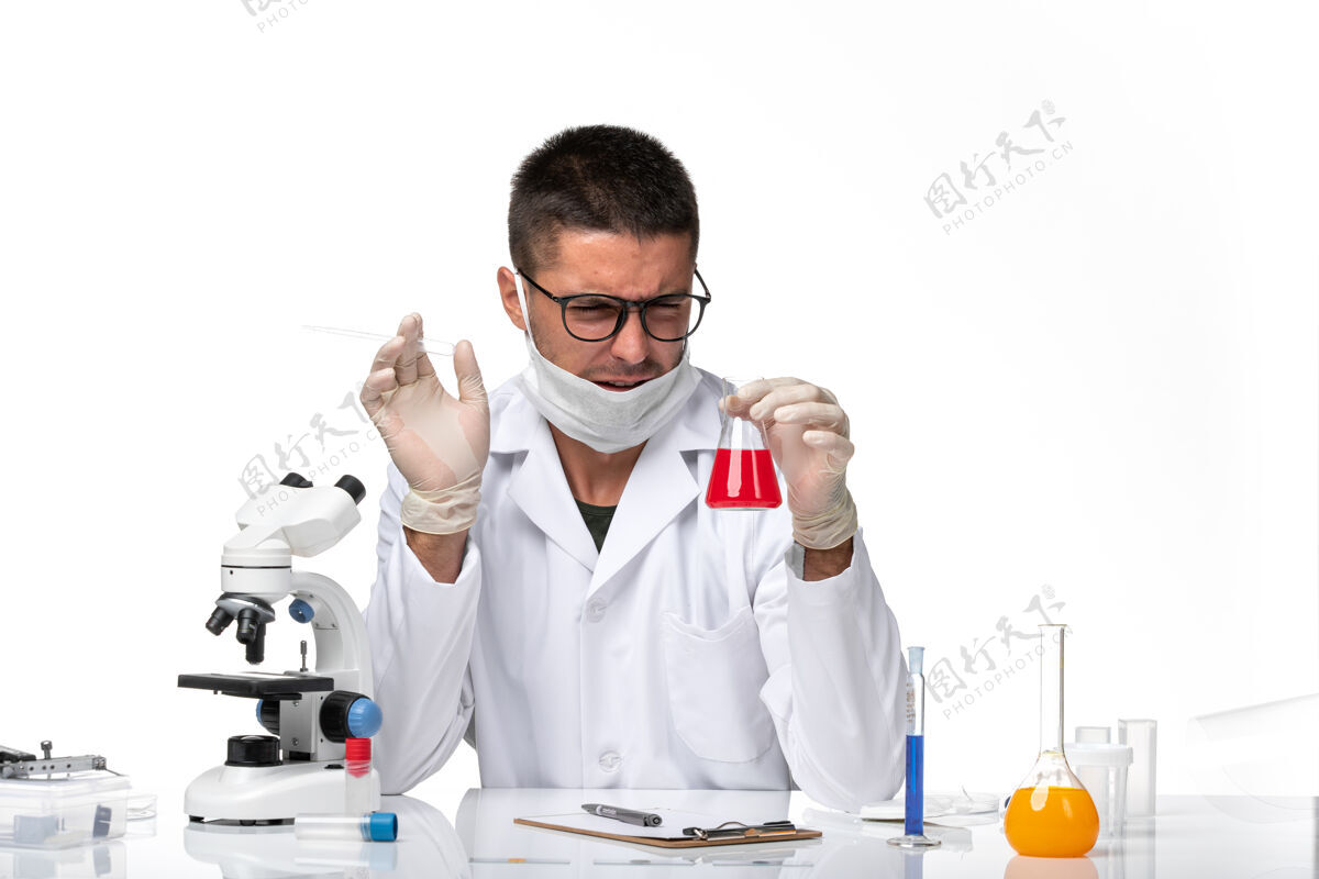 外套正面图：男医生穿着白色医疗服 戴着面罩 在白色空间里放着红色溶液药物套装护具
