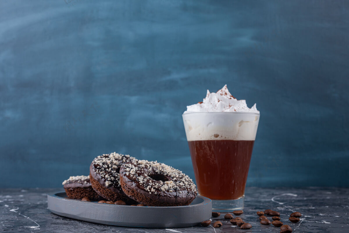 泡沫黑色的巧克力甜甜圈 椰子粉和美味的咖啡 大理石背景背景甜甜圈美味